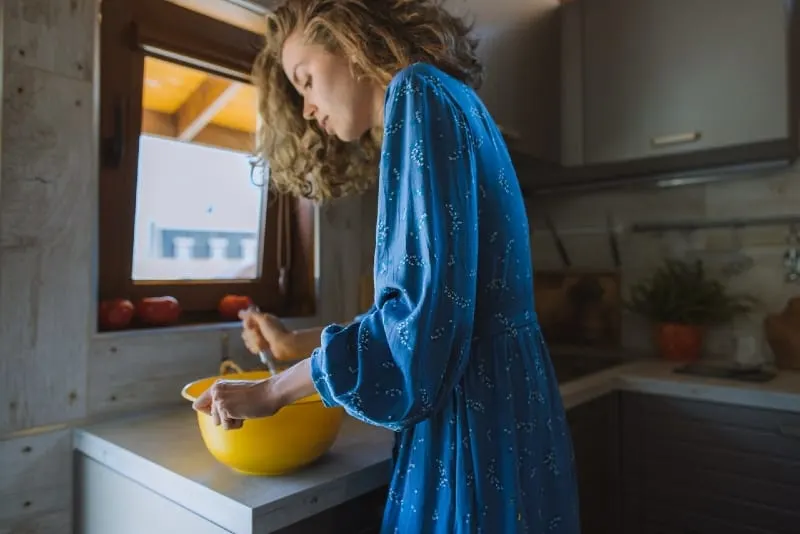 woman holding yellow bowl while standing in kitchen