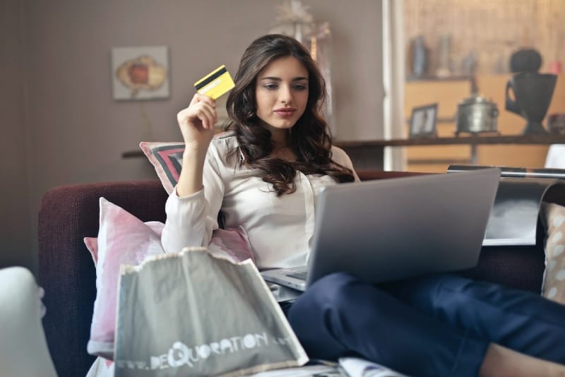 woman holding credit card while looking at laptop