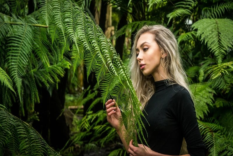 blonde woman in black top holding fern