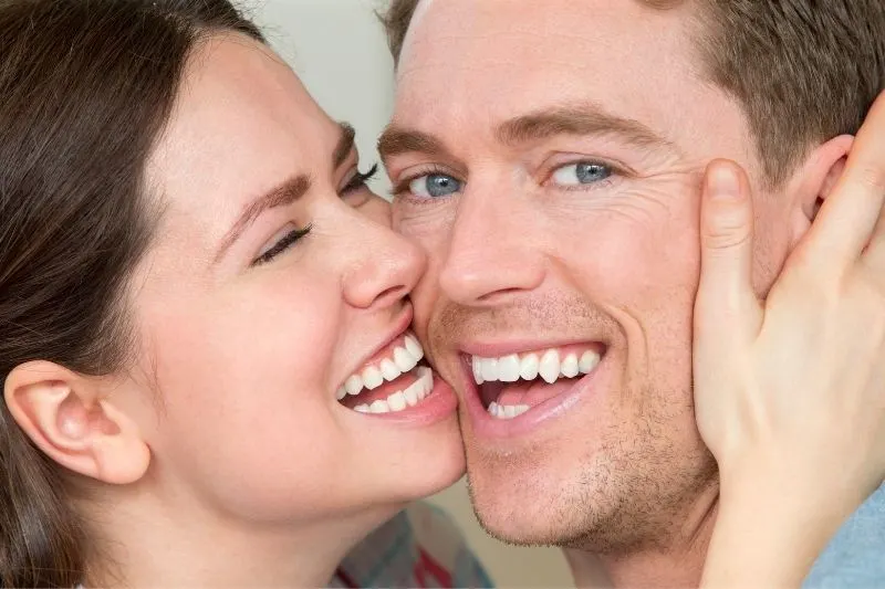 woman holding man's face close to hers laughing focus on the faces