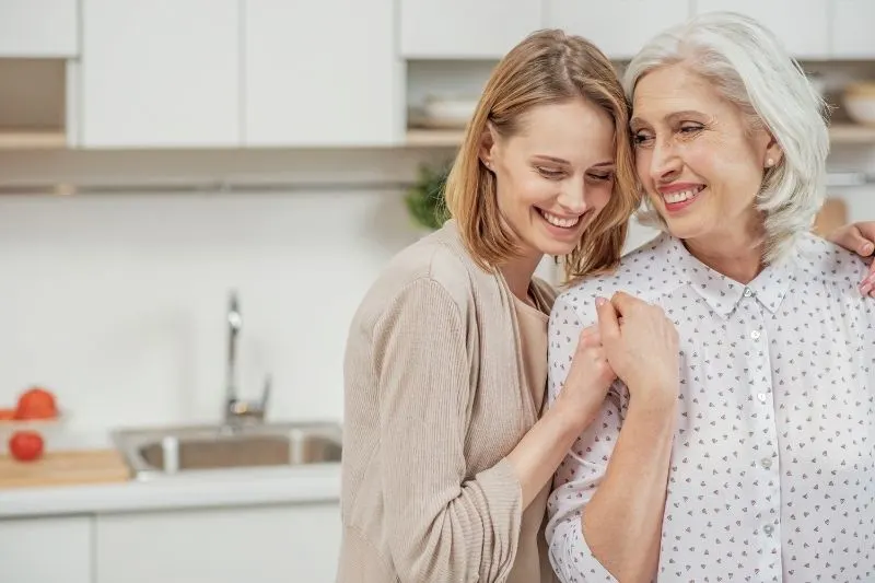 woman hugging an older woman inside the kitchen 