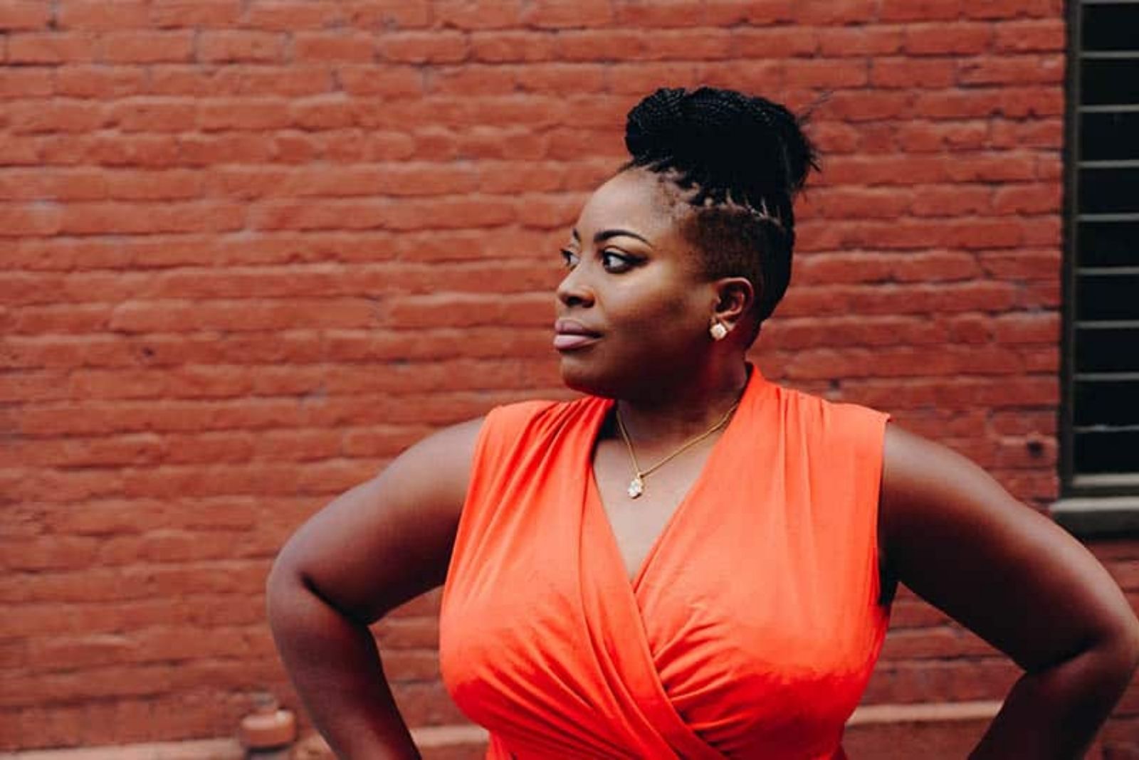 woman in orange dress standing and looking into distance