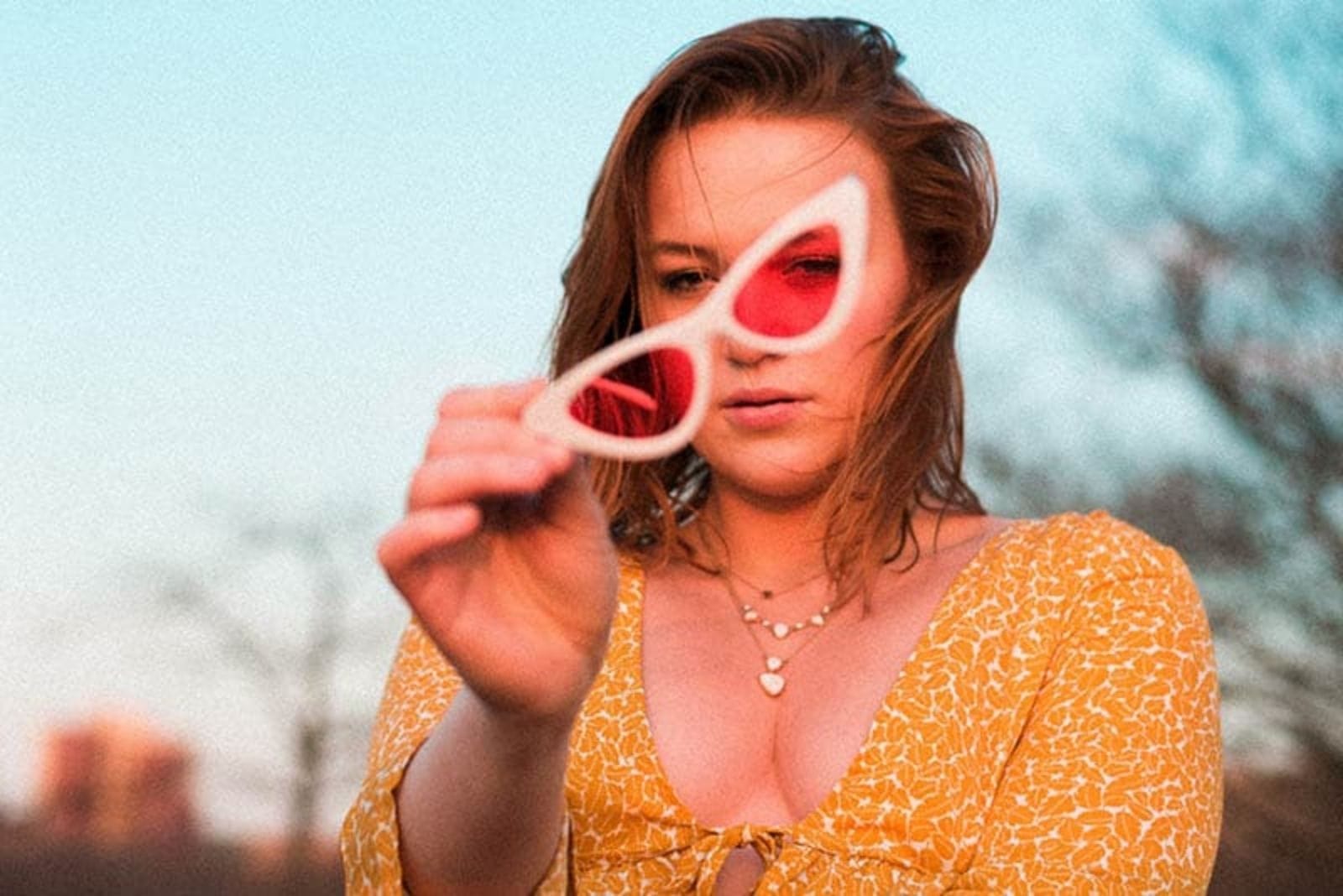 mulher de camisa amarela com óculos de sol cor-de-rosa