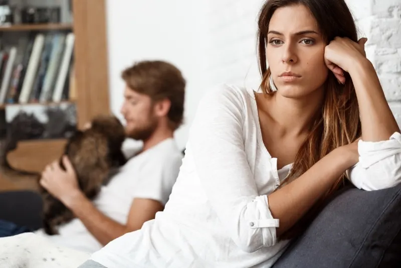 sad woman in white top leaning on sofa
