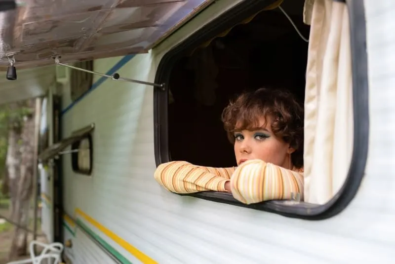 woman in yellow striped top leaning on window of camper