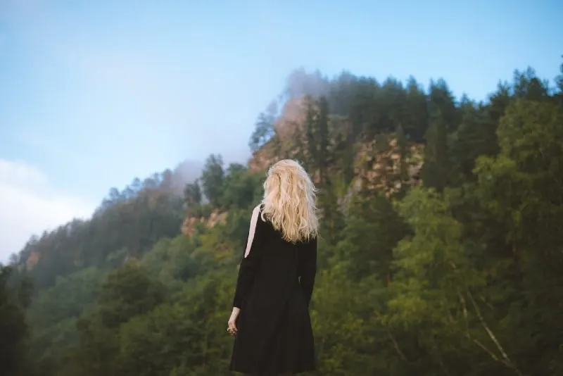 blonde woman in black dress looking at mountain