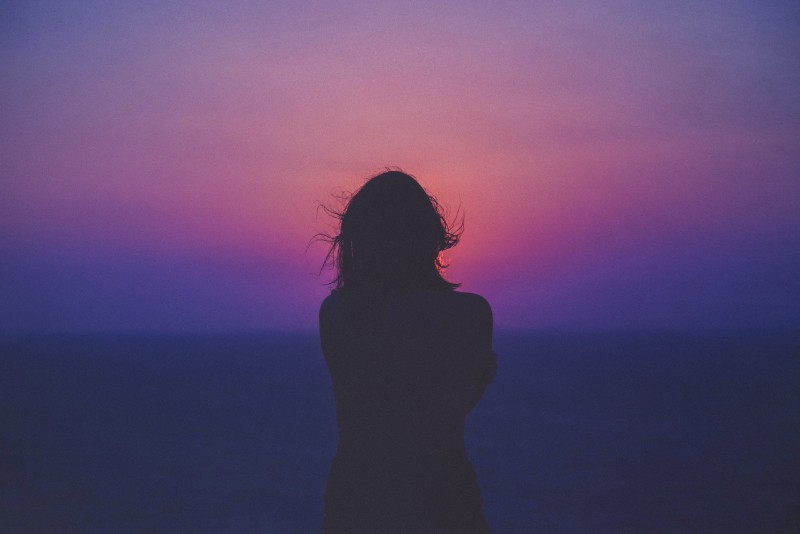 Donna che guarda il mare al tramonto
