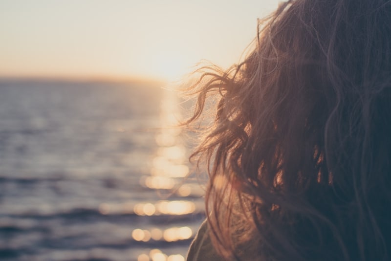 mujer mirando al mar durante la puesta de sol