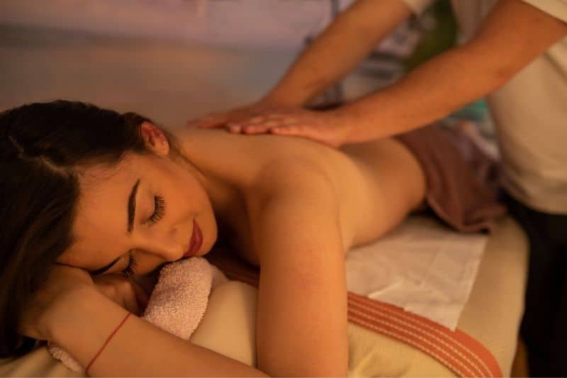 woman lying on a massage table with a therapist massaging her