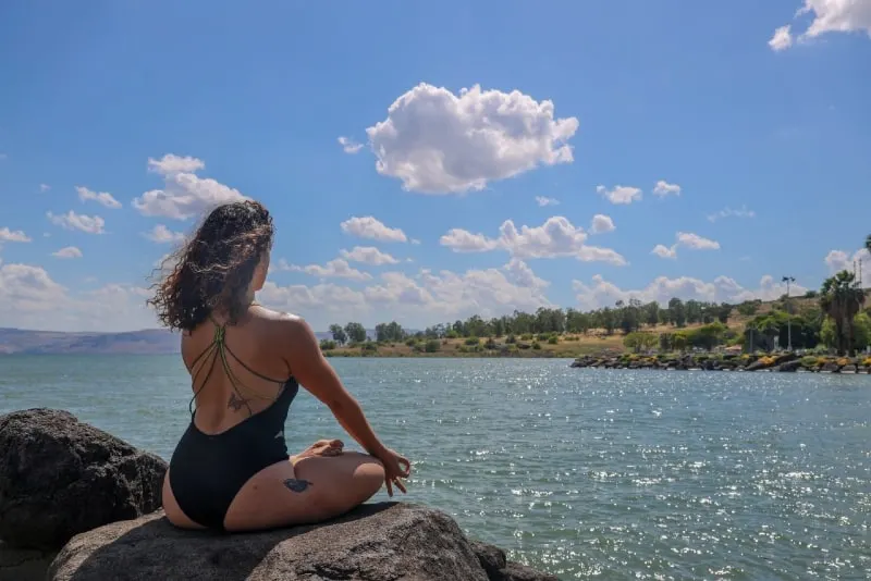 woman in black swimsuit meditate near water