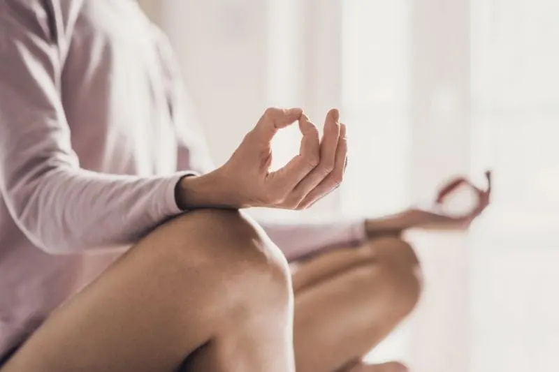 woman meditating at home doing yoga in cropped image