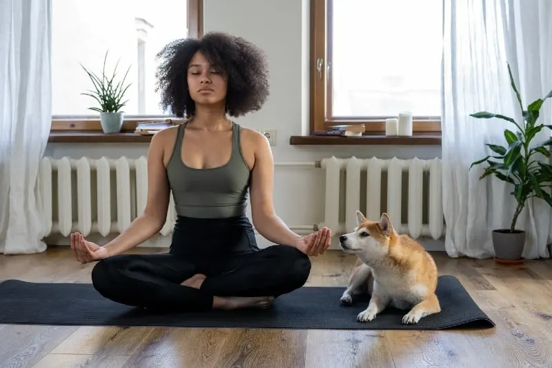 woman meditating while sitting near dog