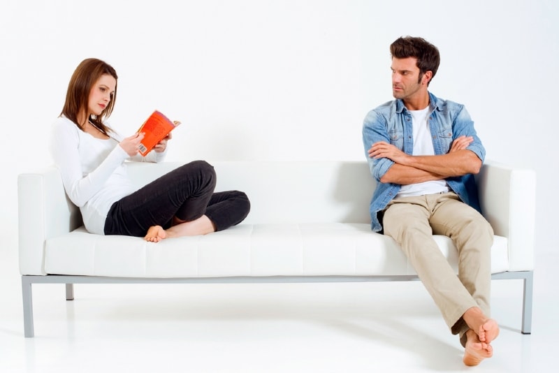 woman reading book while sitting near man
