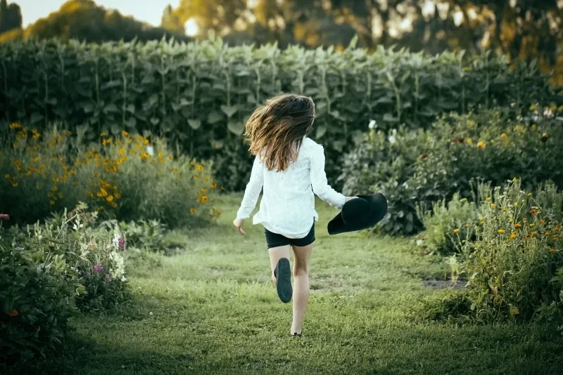 woman in white shirt running on green grass