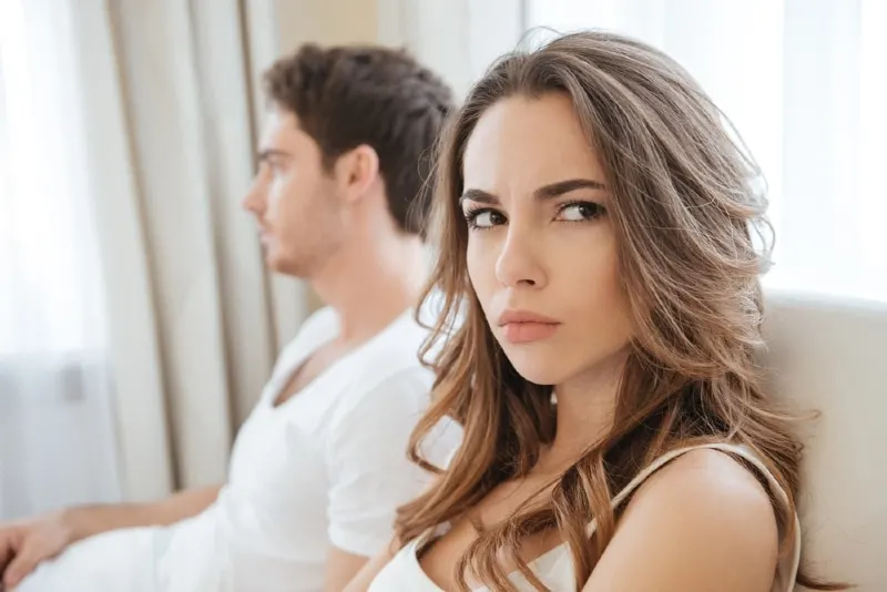 angry woman in white top sitting near man