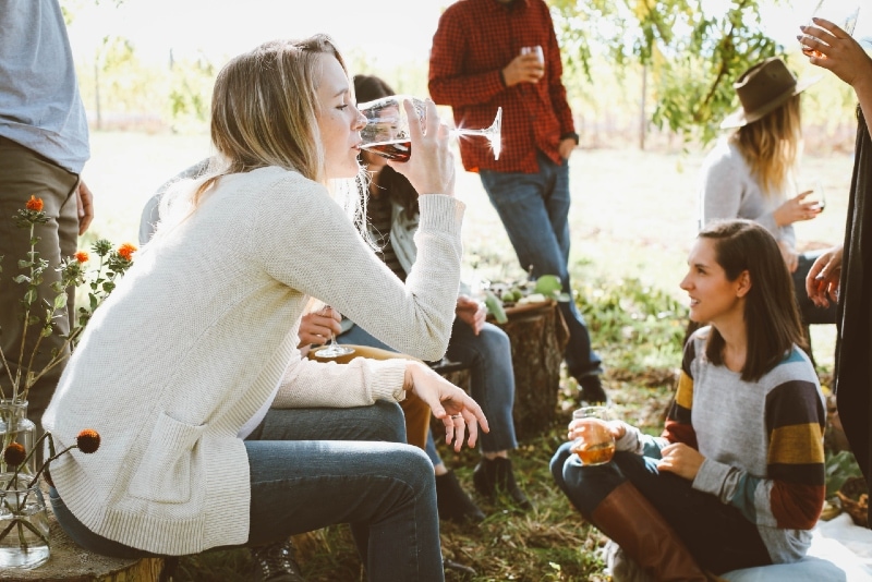 mulher sentada perto de pessoas enquanto bebe vinho