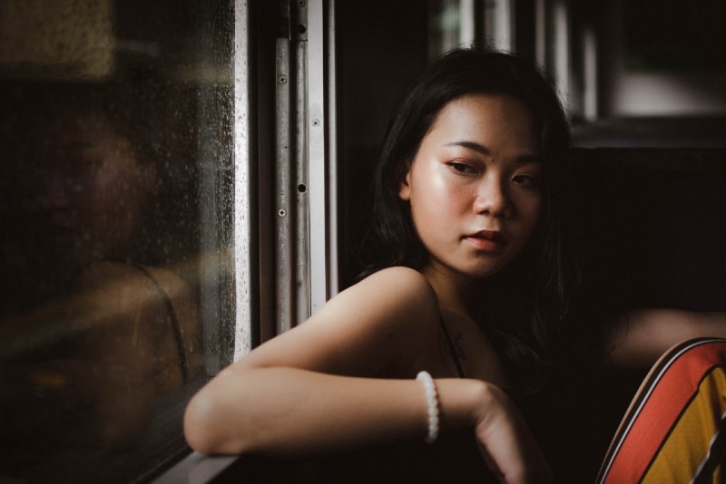 woman with white beaded bracelet sitting near window