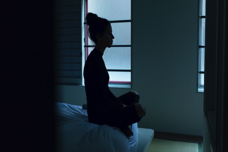 donna in top nero seduta sul letto