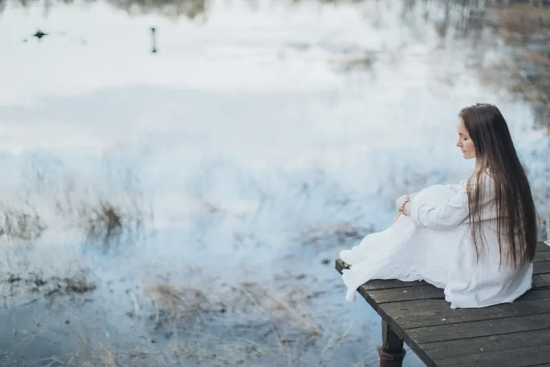 woman in white dress sitting on dock