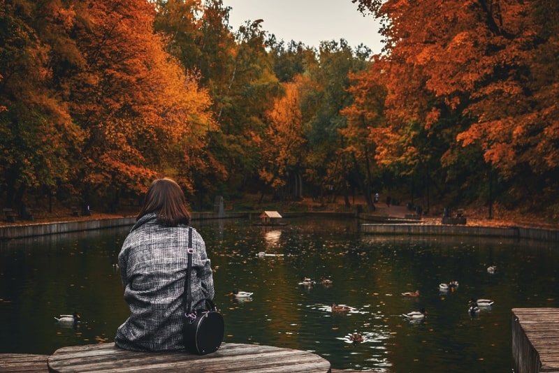 woman with black bag sitting on dock