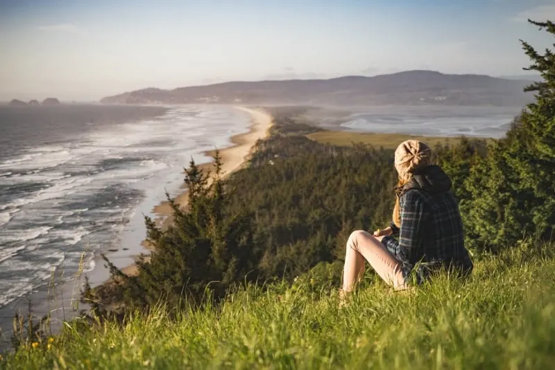 woman sitting on grass looking at ocean