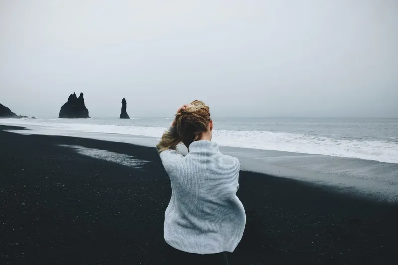 woman in gray sweater sitting on shore