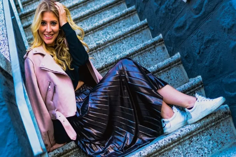 smiling woman in pink jacket sitting on stairs