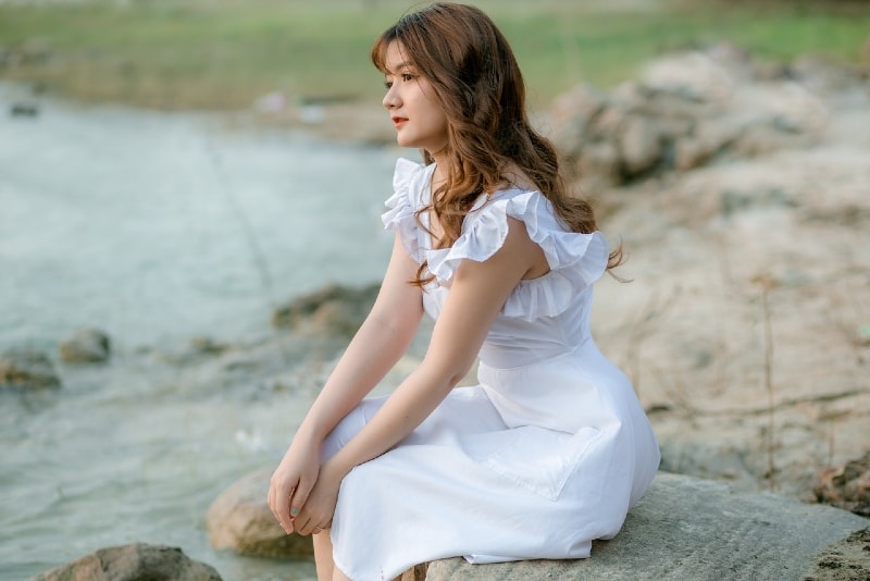 woman in white dress sitting on stone