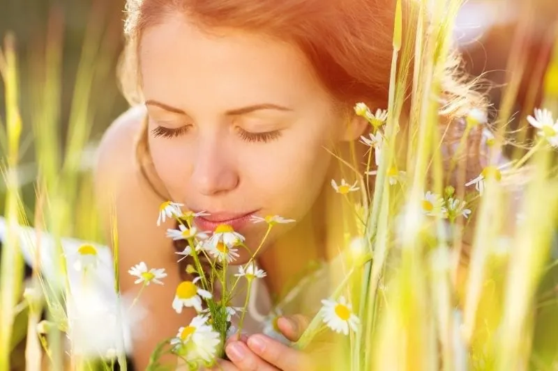 woman smelling daffodils on the field while lying down face in focus