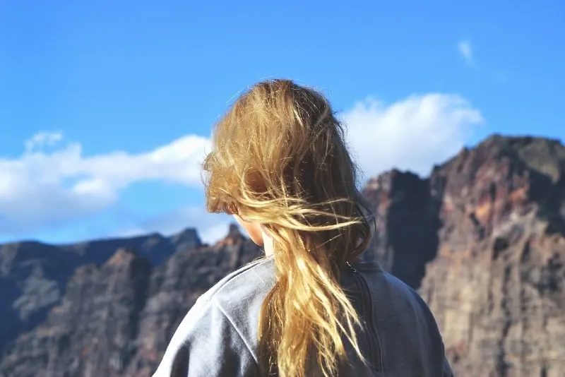 blonde woman in gray sweatshirt standing near mountain