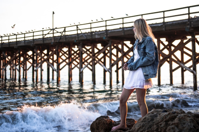 donna con giacca di jeans in piedi vicino al mare