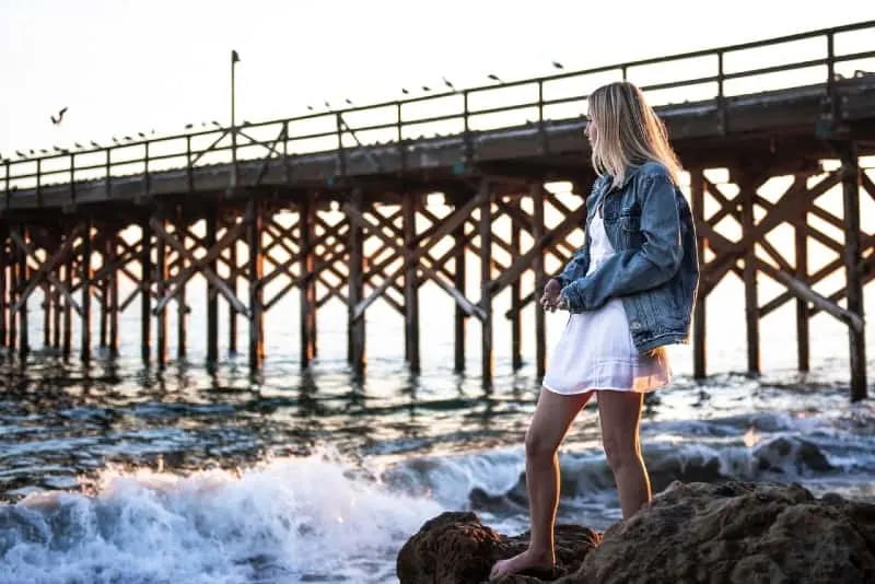 woman in denim jacket standing near water