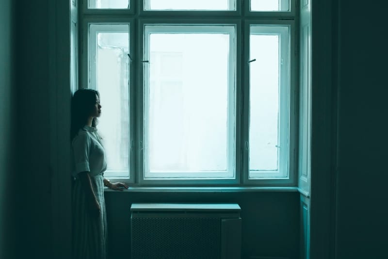 woman in white shirt standing near window