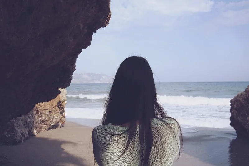 woman standing on beach looking at sea