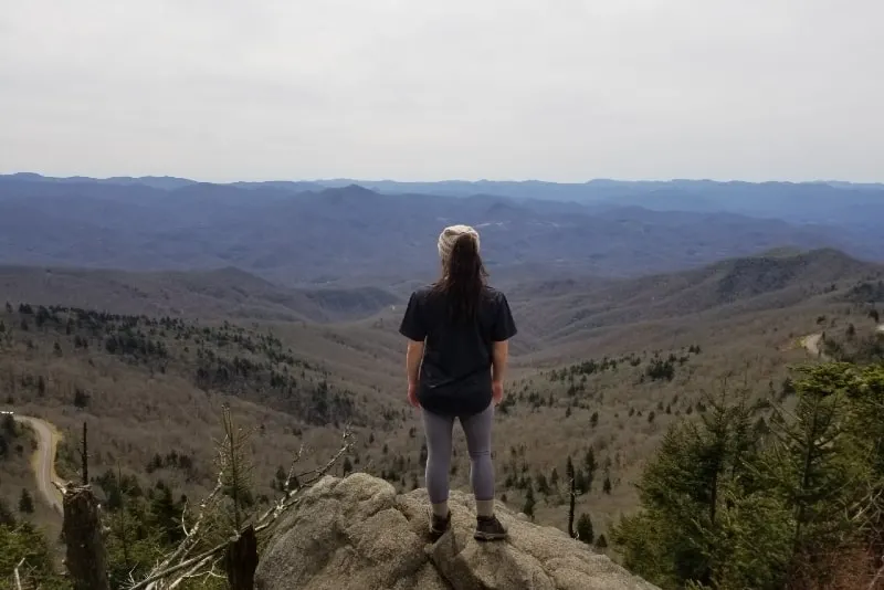 woman standing on rock looking at mountain