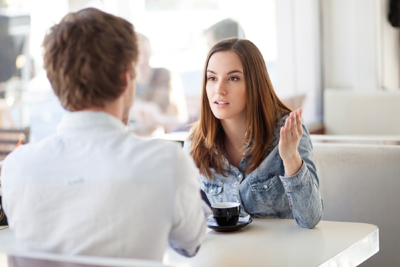 mujer hablando con hombre sentada a la mesa