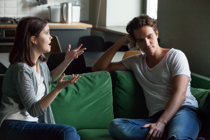 woman talking to man while sitting on green sofa