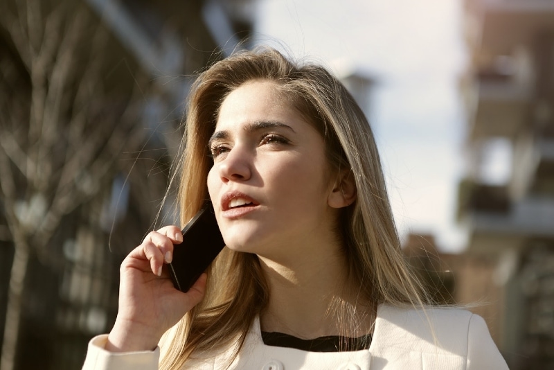 mulher a falar ao telefone em pé ao ar livre