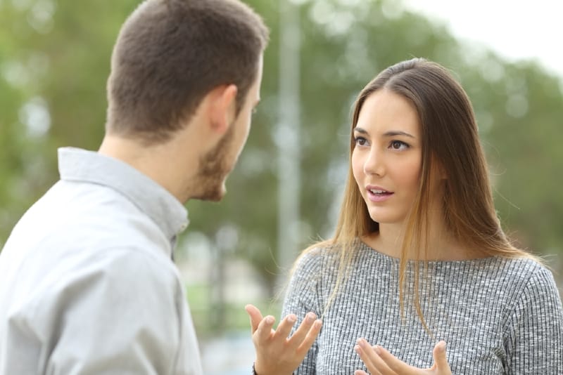 woman in gray sweater talking to man outdoor
