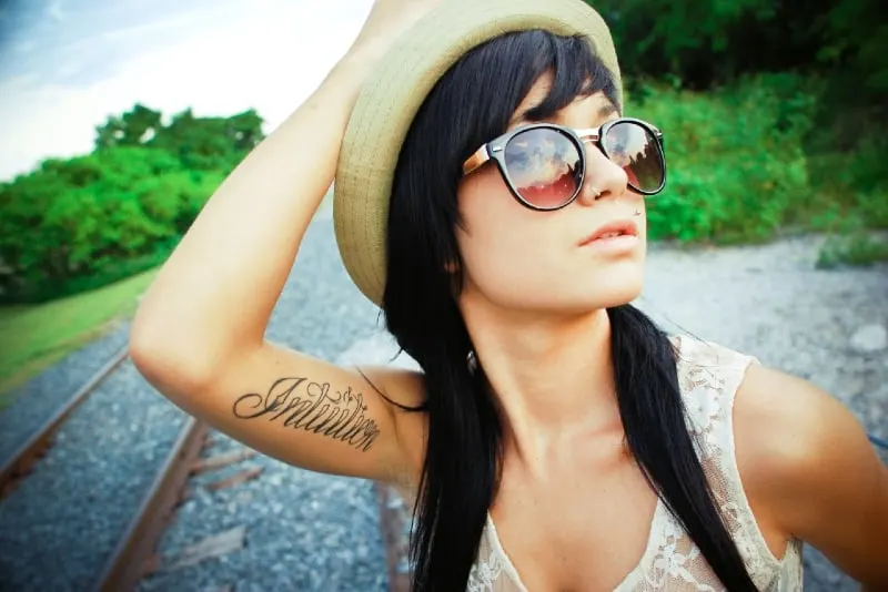 woman with sunglasses touching her hat