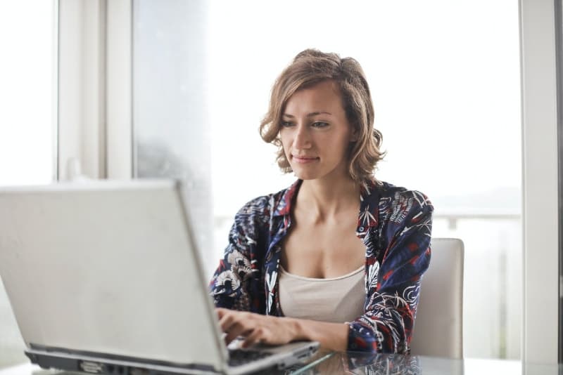 mulher a utilizar um computador portátil enquanto está sentada numa cadeira