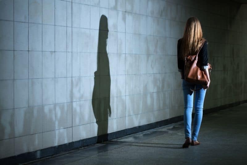 donna che cammina da sola nel buio ombreggiatura sul muro