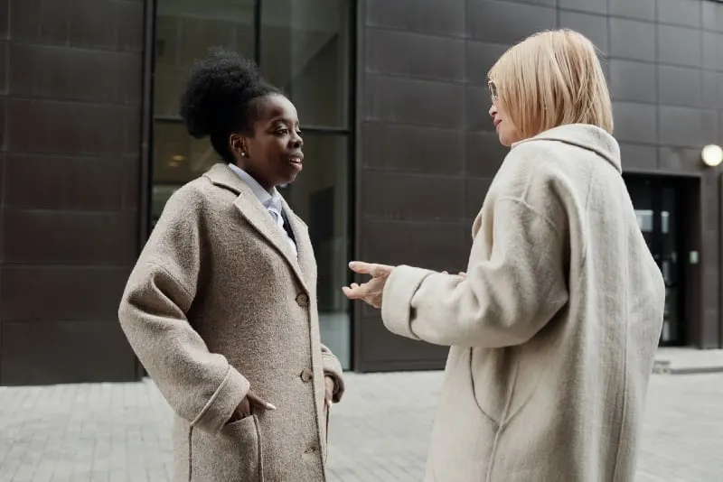 two women in beige coats talking outdoor