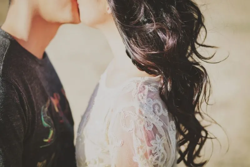 young couple kissing outdoors in cropped image