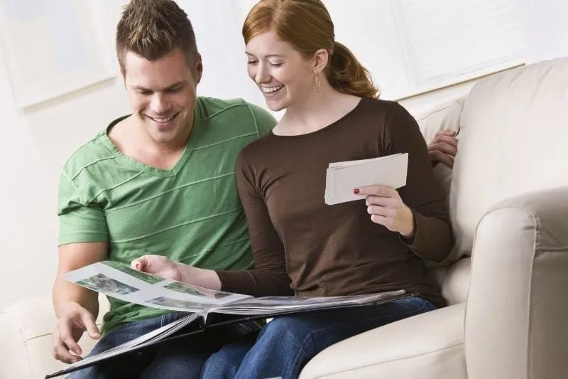 young couple scrapbooking and sitting on a couch