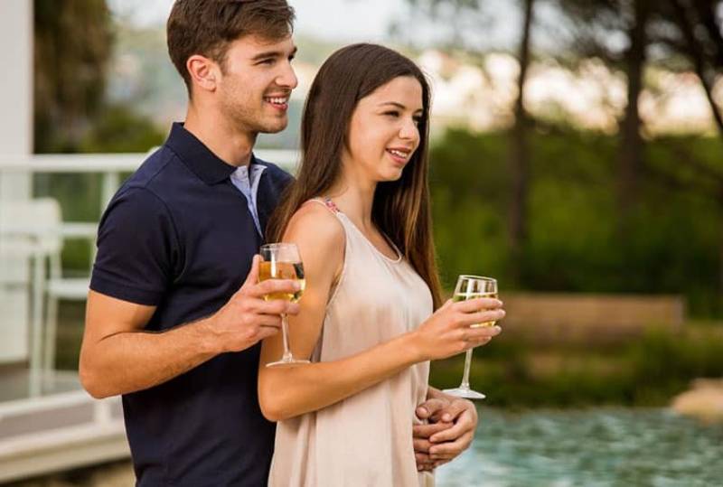 young couple wine tasting while man hugging the woman