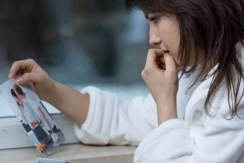 young depressed woman looking at the picture of a couple 