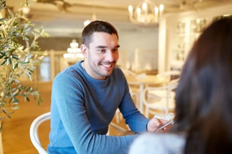 young guy talking to a woman inside a cafe