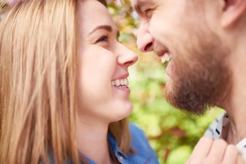 young lovers looking at each other laughing outdoors