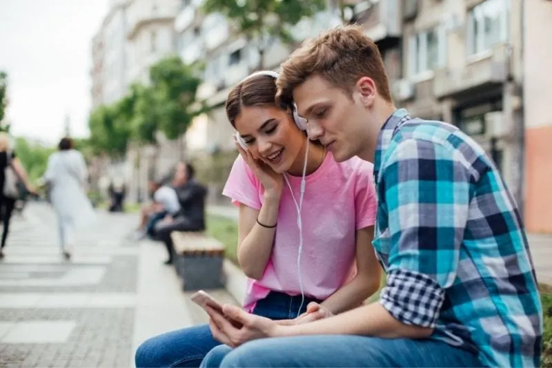 young man and woman listen to music from their phone
